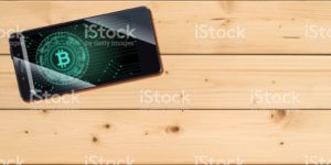 Cryptocurrency concept (A smartphone with a Bitcoin displayed and on the plank)2