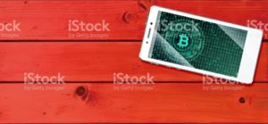 Cryptocurrency concept (A smartphone with a Bitcoin displayed and on the plank)11