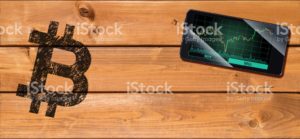 Cryptocurrency concept (A smartphone with Bitcoin chart displayed and on the plank)1